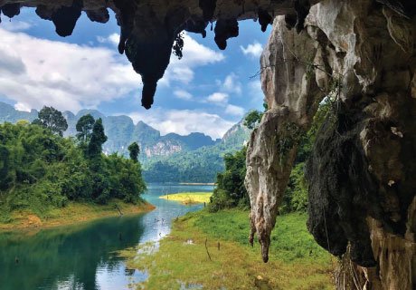 Limestone stalactites framing the emerald water of Cheow Lan Lake in Khao Sok National Park