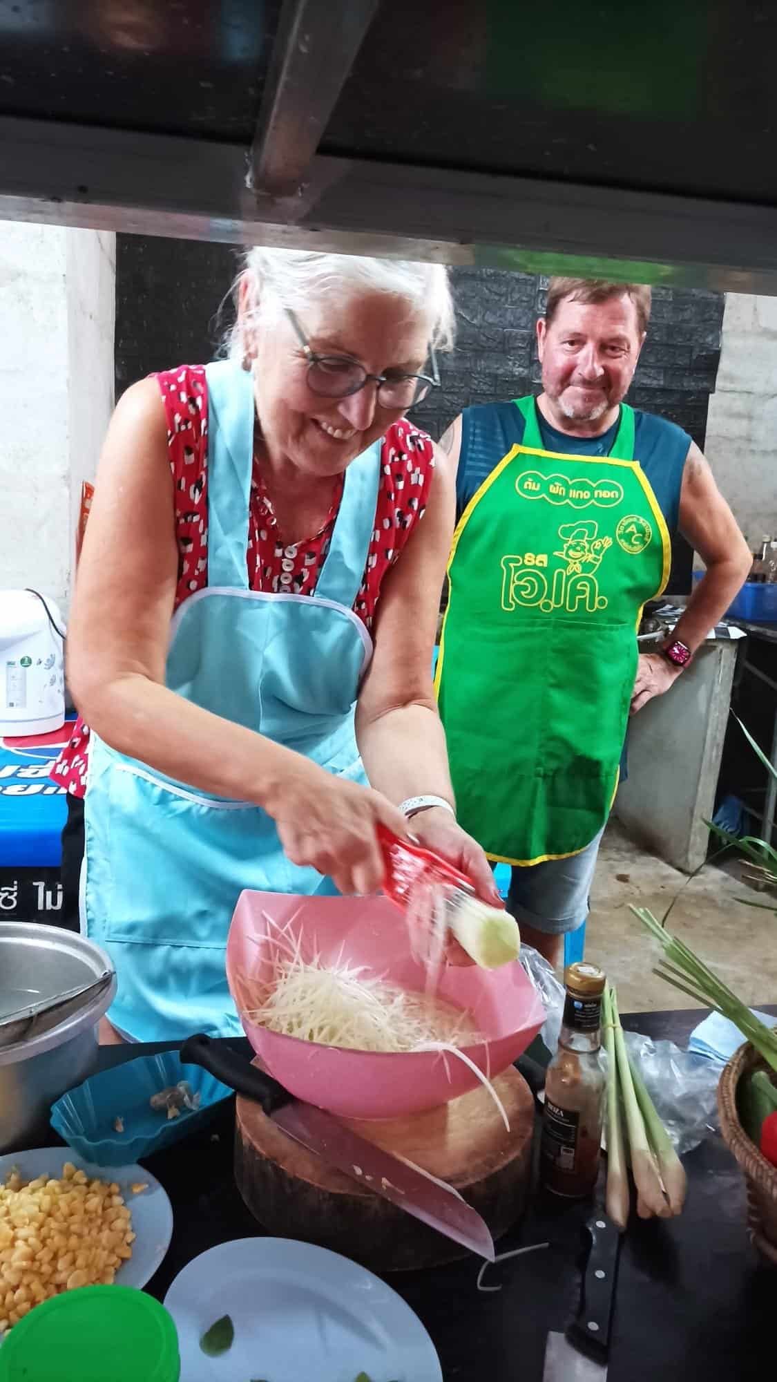 Guest cooking Thai curry in a wok under the guidance of a professional Thai cook in Khao Lak